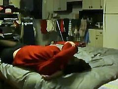 Asian man sitting on a bed in red sweater