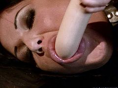 Lascivious brunette babe stands in doggy pose with her legs and hands handcuffed while a perverse domina forces her suck a dildo and later fuck her vagina with it in BDSM-styled sex video by 21 Sextury.