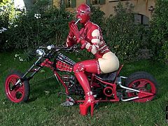 Kinky woman with ample booty and big boobs is wearing latex costume and mask. She is looking hell arousing and mysterious. Secretive woman wanks with sex toy sitting on a big powerful bike.