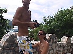 A slim brown-haired milf is getting naughty with some guy outdoors. She kneels in front of the stud and pleases him with a blowjob and a handjob.