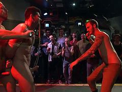 In this gay bar everybody's having fun, except Billy. Billy can't enjoy himself too much because he's being tied up and offered to the public. When he's brought on the stage, completely naked and all tied, the boys go crazy! They cheer him and then begin to fuck the hot brunette sex slave's mouth.