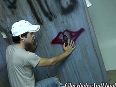 Some Black dude pushes his big dick through the hole in a wall. Orion Cross sucks this cock and also strokes it.