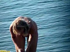 A dude films a slim blonde on a nudist beach. She gets in the water, sunbathes and puts sunscreen all over her body. Her tits are perky and her ass is nice too.