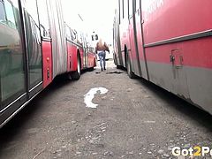Blond haired filthy cutie looks happy pissing between two big buses