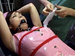 She has been disobeying orders, so the doctor has to tie this latex nurse down. Her mouth is gaged, as she has a vibrator rubbed on her nipples and clit. He spreads her legs wide, so he can see her lovely hairy twat.