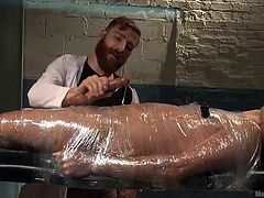 Dean is certainly feeling a little restricted at the moment. He is completely wrapped in plastic wrap, only his nostrils uncovered, so he can breathe. His executor begins the pleasurable torture, using two vibrators to stiffen him up. He unwraps Dean's cock and strokes it, just until he's about to cum.