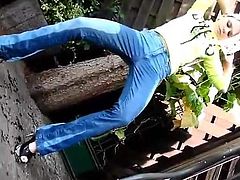 Young blonde standing peeing her jeans in garden and rubs